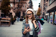 © Davor - Smiling woman shopping with smartphone on city street