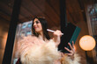 © BullRun - Happy young woman looking at camera holding stylus and tablet, successful female creator in faux fur coat enjoying creative process outdoors, authentic youth and digital lifestyle concept.