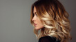 © Helena - Beautiful woman with wavy blonde hair poses gracefully against a neutral background, showcasing her profile and highlighting her elegant features and soft makeup style