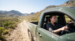 © Xenia - Smiling woman driving a green pickup truck on a dirt road in the mountains. Happy female driver enjoying an off-road adventure and road trip in a rugged landscape