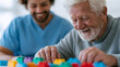 © Alexey - Caregiver assisting senior man with cognitive brain exercise using colorful building blocks. Rehabilitation for elderly patient after stroke or dementia recovery. Memory therapy healthcare.
