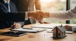 © Ataur400 - Businessmen shaking hands over a deal with a miniature house on the table, symbolizing real estate agreement.
