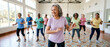 © Rohan Katwe - Diverse group of smiling elderly people participating in gentle fitness class led by joyful senior woman in bright community hall, promoting active aging, wellness, balance, social connection.