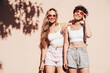 © halayalex - Two young beautiful smiling hipster female in trendy summer white t-shirt and shorts clothes. Sexy carefree women posing in the street. Positive models having fun, hugging and going crazy, near wall
