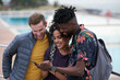 © peopleimages.com - Phone, friends and laugh outdoor with social media, funny joke and sharing text message with lecturer. Happy people, mobile and students with meme, post or show comment for by pool with tutor