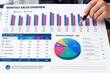 © Ngoc - Annual Sales Report Analysis with Pen Pointing to Revenue Growth Charts and Business Performance Data
