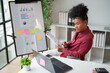 © Tj - African American businesswoman analyzing financial data, reviewing statistics and business reports on documents and a laptop in a modern office for smart planning and development