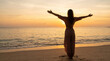 © Formoney - Woman embracing sunrise on tranquil ocean beach shoreline