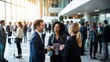 © watcharee - A diverse group of professionals networking and engaging in conversation at a modern corporate event in a bright, spacious venue.