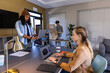 © wavebreak3 - Diverse coworkers working around table in office, woman in tan blazer typing on laptop, copy space