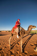 © Cavan Images - woman wearing a turban on a camel tour in the Sahara