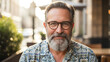 © Lang - Friendly mature adult male with facial hair and spectacles wearing casual attire, smiling sincerely at the viewer in a lifestyle portrait suggesting confidence and happiness.