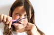 © Katerina - Close up of a young girl cutting her own hair with scissors. Expressive face, natural lighting, concept of DIY haircut and childhood mischief at home.