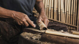 Craftsman skillfully shaping bamboo with sharp tool for traditional flute.
