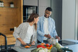 © Daniel - Diverse couple preparing a healthy meal together in a modern kitchen, with the woman chopping vegetables and the man stirring a pot, sharing a pleasant domestic moment