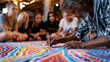 © Maksym - Dot painting master demonstrates the layering of background color fields to a group of teenage community art program participants seated around a large floor canvas in a desert arts center where for