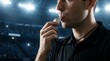 © Pixels Stock - Sports official blowing whistle during competition, stadium at night with bright lights and blurred spectators, close up shot.