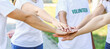 © Pixel-Shot - Group of volunteers putting hands together outdoors