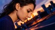 © Everlasting Dreams - Side profile close-up of a woman looking down thoughtfully against a vibrant blurred sunset and city skyline. She wears a purple top and small hoop earring.