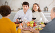 © JackF - Happy carefree young sharing stories and laughing with aged parents at family celebration with wine at cozy home environment..