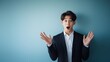 © Maika - スーツを着てカメラ目線で驚く若い日本人男性・ビジネスマンの上半身ポートレート。青い背景と左側に広いコピースペース