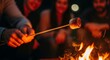 © Лена Федотова - Close-up of hands holding toasted marshmallow over campfire