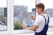 © New Africa - Professional worker tinting window with foil indoors