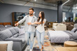 © Serhii - Young couple choosing new sofa in furniture store