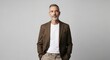 © Ariestia - Confident Mature Businessman in Smart Casual Brown Blazer and White T-shirt Standing Against Neutral Grey Background