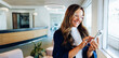 © Julia - Smiling woman uses smartphone in lobby