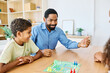 © Lumos sp - Portrait of a happy african american family at home, having fun playing a board game challenge game, playing board game ludo at home
