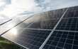 © standret - Solar panels installed in a green field under a bright sky, showcasing renewable energy technology with reflections on the glass surface and grass in the foreground