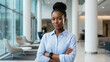 © Stocky Boi - Confident Black businesswoman standing with arms crossed in a bright modern office.
