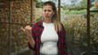 © Krakenimages.com - Woman pointing thumb over shoulder inside building, wearing red plaid shirt and white tee; annoyance refusal.