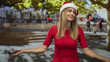 © Krakenimages.com - Woman in santa hat and red top shrugs with open hands and palms up beside steps on street plaza; merry celebration.