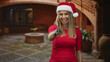 © Krakenimages.com - Woman wearing santa hat and red top extends gloved hand for handshake in building entrance, smiling warmly; festive greeting joyful.