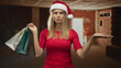 © Krakenimages.com - Woman holding shopping bags while shrugging with palm up in unfinished brick building; holiday frustration.