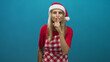 © Krakenimages.com - Woman wearing santa hat and checkered apron holds finger to lips for silence in studio; playful secrecy.