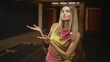 © Krakenimages.com - Woman showing open palms and smiling in studio with wooden beams and warm dim lighting; welcoming warmth.