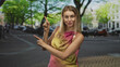 © Krakenimages.com - Woman pointing finger with both hands on a leafy urban street near parked cars and cobblestones; playful invitation.