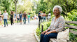 © Xenia - Smiling elderly Black woman sitting on a park bench with a book. Happy senior african american female pensioner enjoying a sunny day outdoors