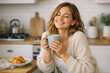 © vefimov - A cheerful young lady savoring a hot beverage and croissant at home.