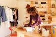 © Artem Podrez/Stocksy - Businesswoman using laptop in clothing store workspace