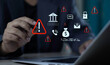 © sarach - Businessman using laptop with bank fraud warning hologram. Financial scam detection and cybersecurity alert icons on money, email phishing, and phone risk.