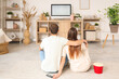 © Pixel-Shot - Young couple watching TV at home, back view