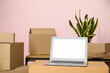 © Pixel-Shot - Blank laptop with moving boxes near pink wall, closeup