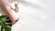 © AMH FX STOCK - Rolled pink yoga mat with water bottle and green leaf on white wooden floor