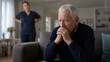 © Lilu - Upset senior man sitting on sofa while aggressive caregiver woman stands behind him. Concept of elder abuse and neglect in nursing home. Awareness for World Elder Abuse Awareness Day.
