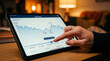 © Masarts - Person Touching Portfolio Value History Chart on Tablet in Warm Home Setting