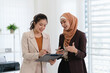 © mojo_cp - Two business colleagues multiethnic working in office, asian muslim